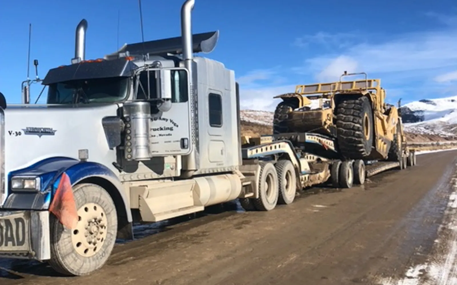 Scraper transported on lowboy behind a semi